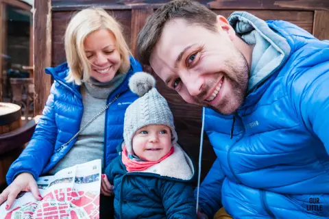 Rodzina zwiedza Lwów na Ukrainie. Uśmiechnięci rodzice i dziecko z mapą.