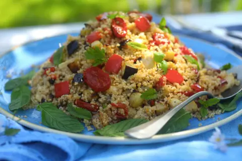 Piatto colorato di cous cous integrale con verdure miste, pomodorini e basilico. Un'idea gustosa per le tue cous cous integrale ricette.