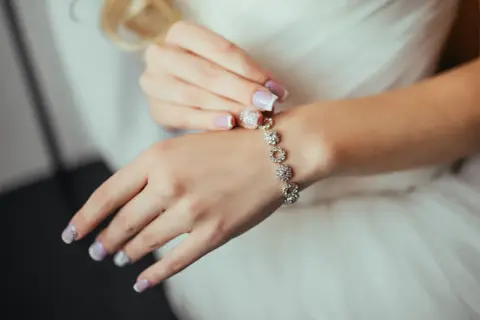 Delikatna bransoletka na ślub, zdobiona błyszczącymi kamieniami, idealnie komponuje się z dłonią panny młodej.
