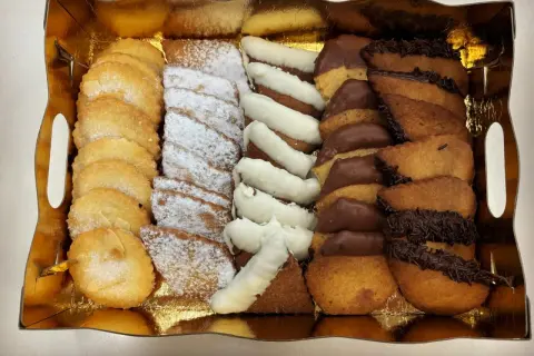 Bandeja dorada con surtido de galletas: almendradas, espolvoreadas con azúcar glas, bañadas en chocolate blanco y negro. ¡La mejor pastelería Zaragoza!