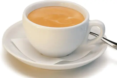 Ein kleiner brauner Kaffee mit Milchschaum in einer weißen Tasse auf einer Untertasse.