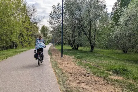 Osoba na rowerze jedzie ścieżką wzdłuż zielonego parku. To piękna pogoria 3 trasa, idealna na wiosenną przejażdżkę.