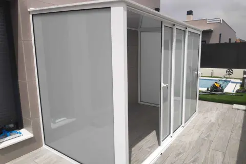 Moderno cierre para balcones y terrazas con puertas correderas de cristal y panel opaco.