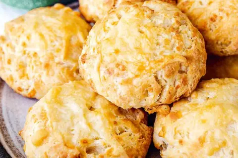 En hög med gyllene, fluffiga ostscones, perfekta för en mysig fika.