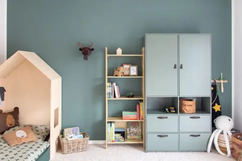 Gemütliches Kinderzimmer für Grundschulkinder mit Hausbett, Bücherregal und Spielzeug.