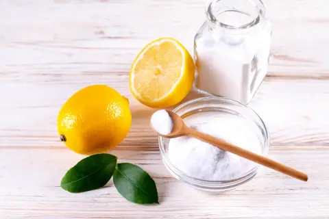 Limoni, bicarbonato e una ciotola con la struttura dell'acido citrico, pronti per un rimedio naturale.