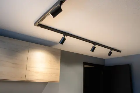 Svart spotlightskena med flera justerbara lampor ger modern belysning hall inspiration. Ljuset träffar ljusa träskåp.