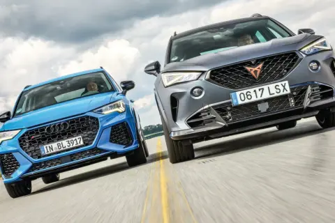 Niebieskie Audi RS Q3 i szare Cupra Formentor, dwa najlepsze SUV-y, pędzą po drodze.