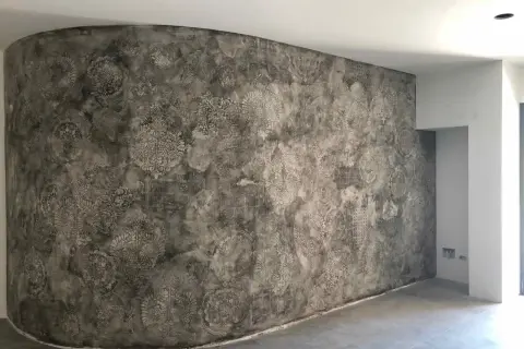 Parete curva con un suggestivo intonaco a calce decorato con motivi floreali e geometrici in stile damascato.