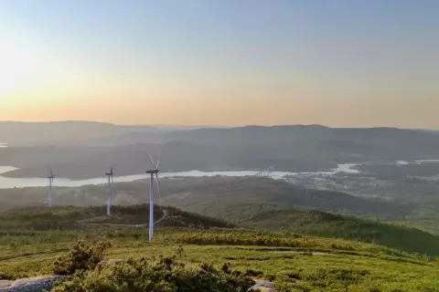 Vistas del monte Xiabre con molinos de viento y un río al atardecer.
