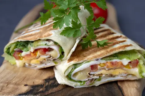 Pyszna tortilla z jajkiem, serem, warzywami i kurczakiem, podana na desce.