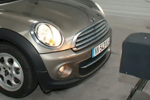 Réglage des feux diurnes d'une Mini Cooper marron, avec un appareil de mesure à droite.