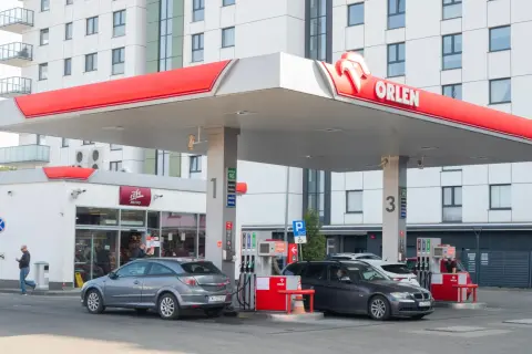 Stacja Orlen z dystrybutorami paliwa. W tle nowoczesny budynek mieszkalny. Ceny paliw, w tym akcyza, wpływają na koszty tankowania.