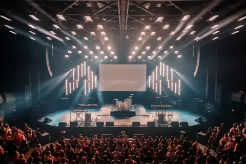 An empty concert stage with drums and keyboards awaits the band. The audience is seated, ready for the show to begin, and wondering what is the average length of a concert.