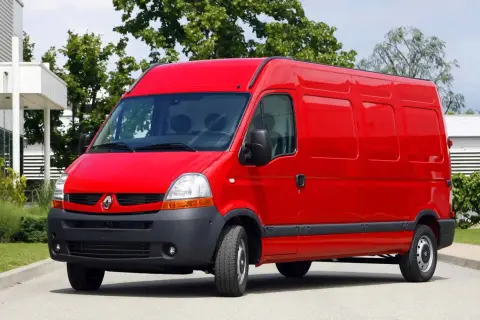 Czerwony Renault Master 2, gotowy do pracy, stoi na tle zieleni i nowoczesnego budynku.