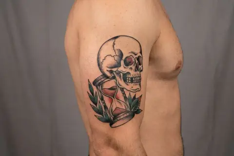 Ein Tattoo mit einem Totenkopf und einer Sanduhr, ein Symbol für die Vergänglichkeit des Lebens.