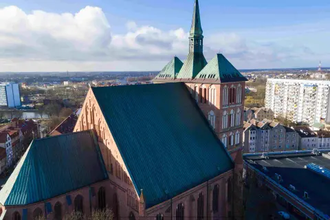 Imponująca katedra góruje nad panoramą jednego z miast w zachodniopomorskim. W tle widać blokowiska i inne budynki.
