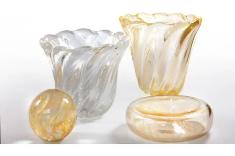 Vasi e oggetti decorativi in vetro soffiato, con fili dorati e bianchi, che evocano la maestria di Seguso Vetri d'Arte.
