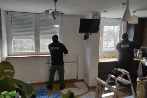 Montaż rolety zewnętrznej we wnęce okiennej. Pracownicy firmy "Osłony Okienne" montują rolety, zapewniając komfort i bezpieczeństwo.