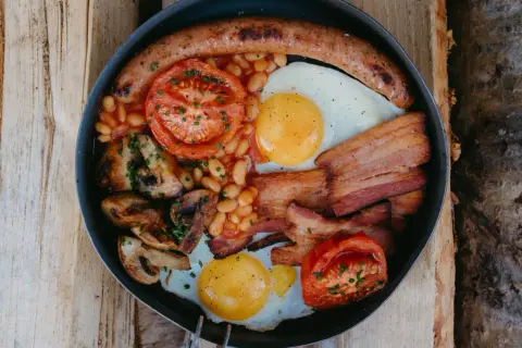 En rejäl engelsk frukost i en stekpanna: korv, ägg, bacon, bönor, tomater och champinjoner.