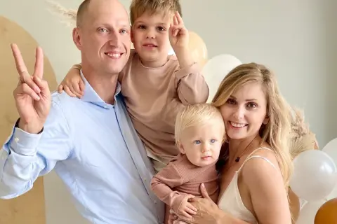 Katarzyna z mężem i dziećmi, uśmiechnięci, w otoczeniu balonów.