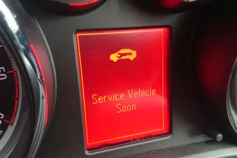 Wyświetlacz w Oplu Astrze H z komunikatem "Service Vehicle Soon" i ikoną samochodu.