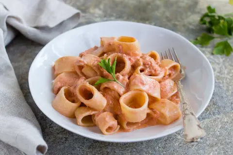 Un piatto di pasta al tonno cremosa, con paccheri conditi e guarniti con prezzemolo fresco.
