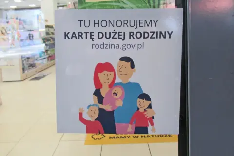 Plakat informuje, że honorowana jest karta dużej rodziny. Widnieje na nim rysunek rodziny z dwójką dzieci i niemowlęciem.