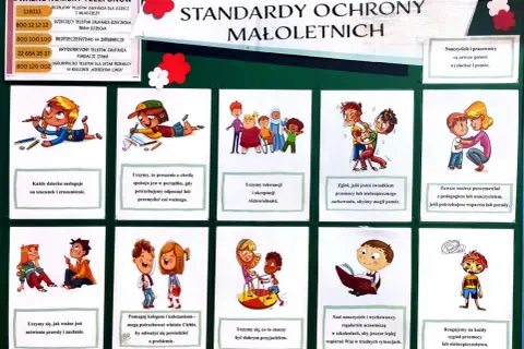 Tablica z ważnymi numerami telefonów i standardami ochrony dzieci. Widać rysunki dzieci, np. bawiące się, uczące, pomagające sobie. Reagujemy na każdy sygnał przemocy.