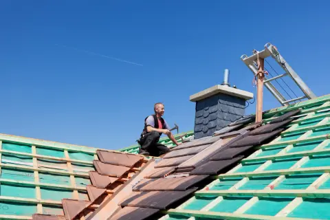 Budowa dachu dwuspadowego 100m2. Ciesla układa dachówki.