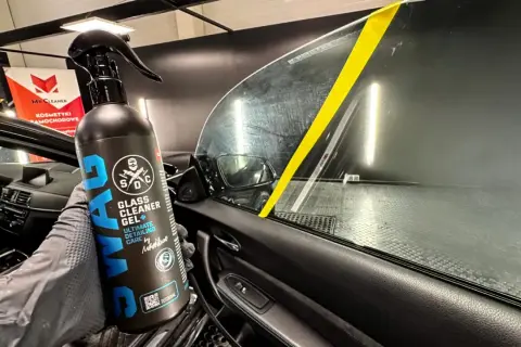 Rękawica z preparatem SWAG Glass Cleaner Gel pokazuje, czym umyć szyby w samochodzie. Żółta taśma na szybie wyznacza obszar czyszczenia.
