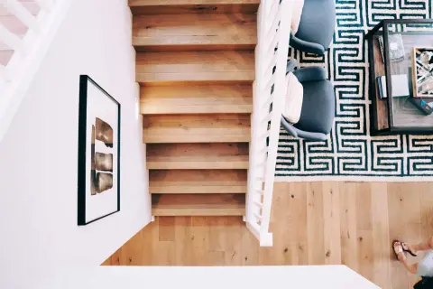 Renovera trappa med matta: en modern trappa i trä med vit balustrad, en grafisk matta och två fåtöljer.