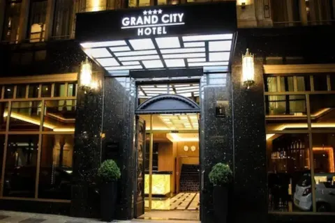 Elegancki **grand city hotel** nocą, z podświetlanym neonem i lśniącym wejściem.