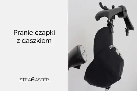 Jak prać czapkę z daszkiem? Czarna czapka zawieszona na wieszaku, obok parownica.