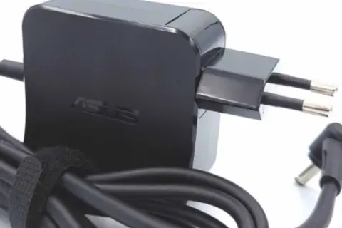 Czarny zasilacz Asus z wtyczką europejską i kablem. Dowiedz się, jak dobrać zasilacz do laptopa, by zapewnić mu bezpieczne ładowanie.