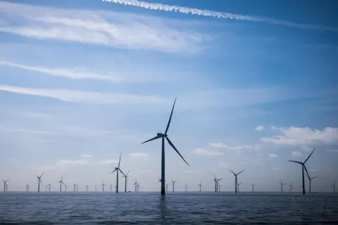 Ogromne farmy wiatrowe na Bałtyku, z wiatrakami na tle błękitnego nieba z chmurami.