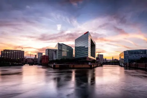 Spektakulärer Sonnenuntergang über Hamburgs moderner Architektur. Ein perfekter Ort für Fotospots Hamburg, mit Spiegelungen im Wasser.