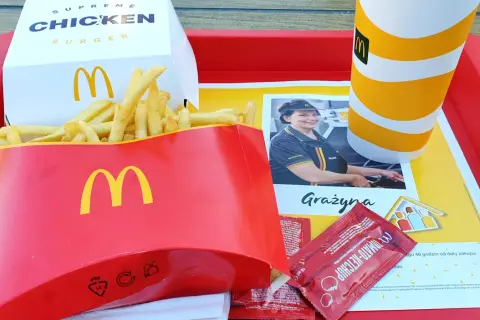 Na tacy McDonald's: duża porcja frytek, burger supreme chicken, napój i ketchup. Zastanawiasz się, ile kosztują duże frytki w maku?