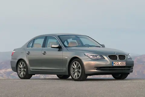 Szary sedan BMW 535d na tle górskiego krajobrazu.