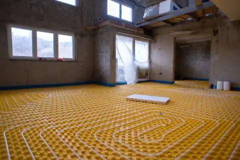 Installazione di un sistema di riscaldamento a pavimento, un'avanzata forma di aria condizionata a pavimento, in un edificio in costruzione.
