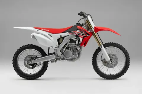 Czerwono-biały motocykl crossowy Honda z widocznym silnikiem i kołami.