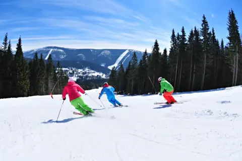 Skifahrer genießen die Pisten in Spindleruv Mlyn. Ein sonniger Tag mit Blick auf die Berge und den Wald.