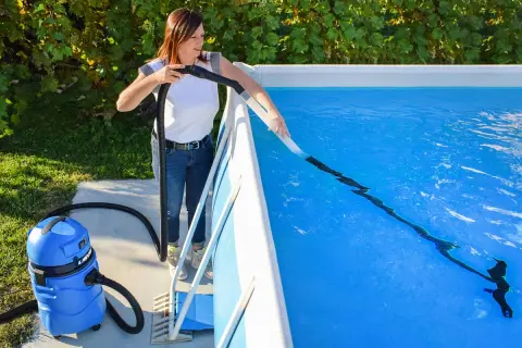 Donna usa un aspiratore per pulire il fondo della piscina, un metodo efficace per capire come pulire la piscina dopo averla svuotata.