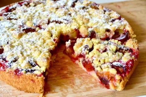Saftiger Zwetschgenkuchen aus Hefeteig in einer Springform, bestreut mit Puderzucker und Streuseln.