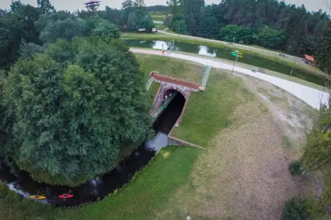 Akwedukt w Fojutowie, gdzie rzeka przepływa pod ziemią, a nad nią rozciąga się malowniczy park z jeziorem i wieżą widokową.