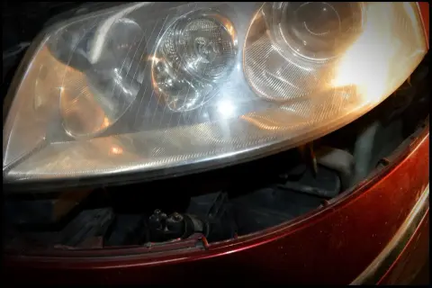 Reflektor Passat B5 FL, widok na żarówki przód. Widać fragment czerwonego lakieru i wnętrze lampy.