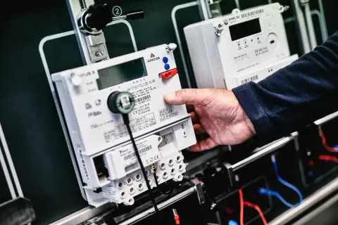 Dłoń manipuluje przy liczniku energii elektrycznej, przygotowując go do przepisania licznika PGE.