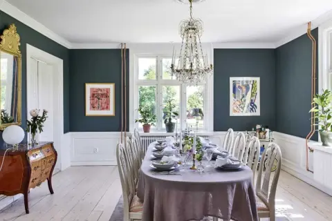 Elegant matsal med dukat bord, kristallkrona och konst. En vacker inspiration för att renovera sekelskifteshus.