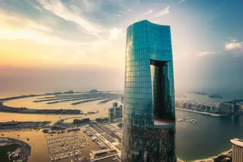 Imponujący, szklany wieżowiec, najwyższy hotel na świecie, góruje nad Dubajem o zachodzie słońca. Widok na sztuczne wyspy w kształcie palmy.