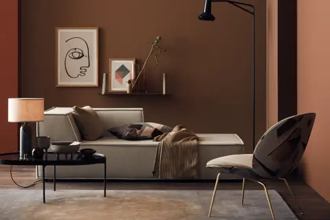 Gemütliches Wohnzimmer in warmem Braunton mit Sofa, Sessel und Kunst.